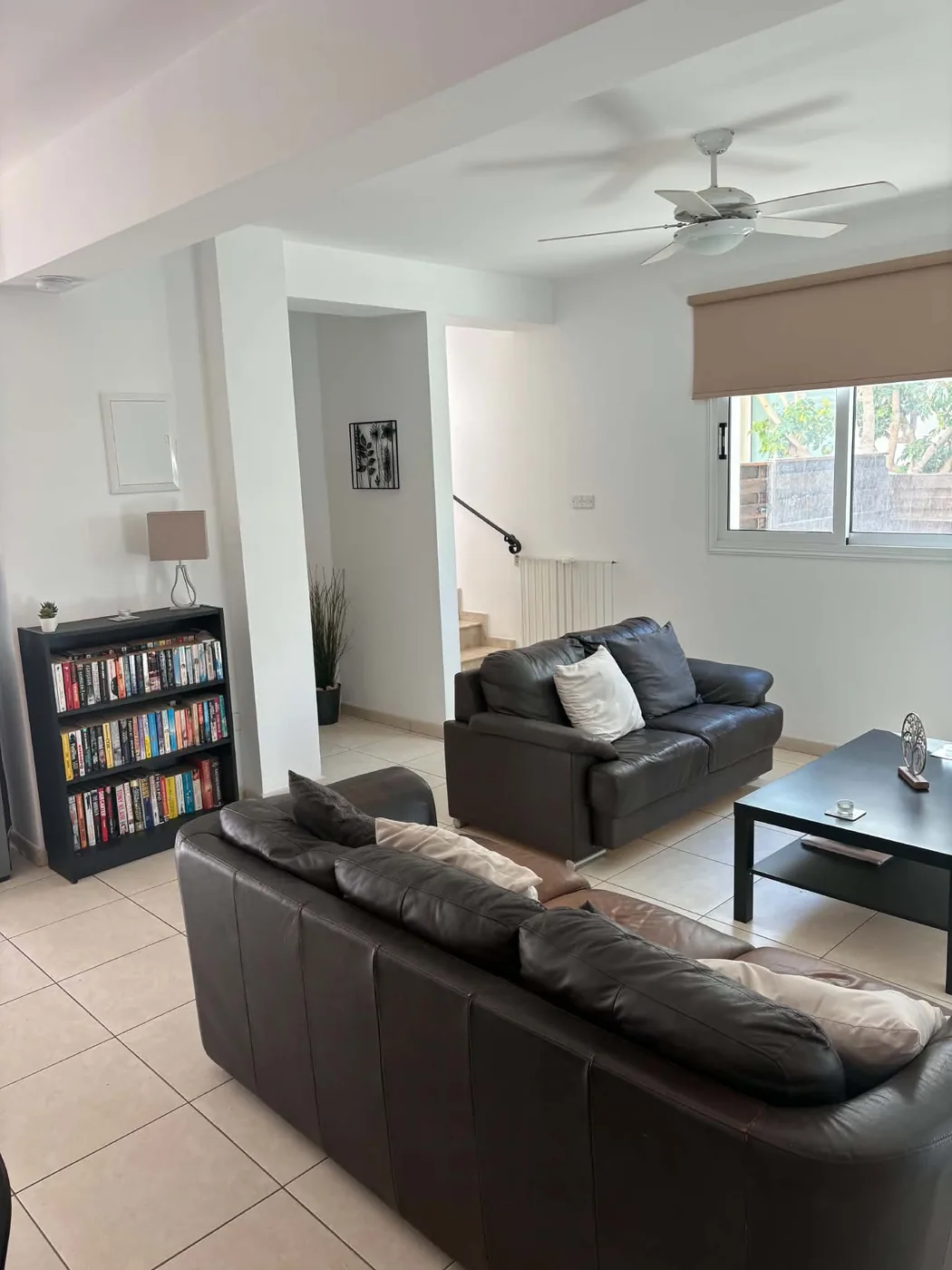 Palm Villa spacious lounge with leather sofas, bookcase and staircase